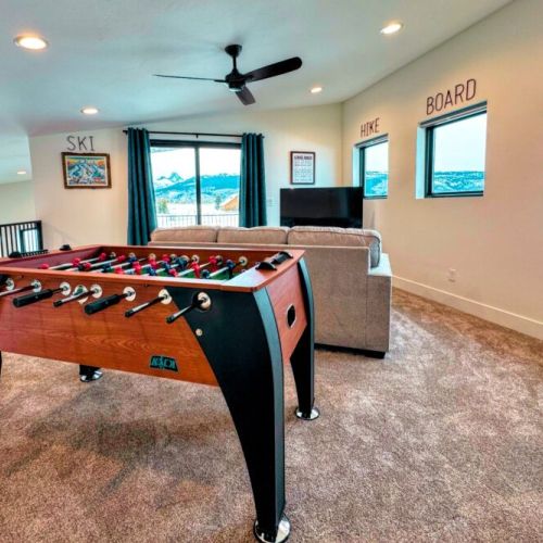 The upstairs living area has its own TV, a dedicated workspace, a foosball table, and a balcony with spectacular views of the mountains.