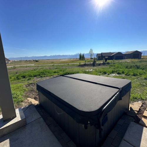 The hot tub is off the lower porch, accessible from the downstairs queen bedroom or through the garage.
