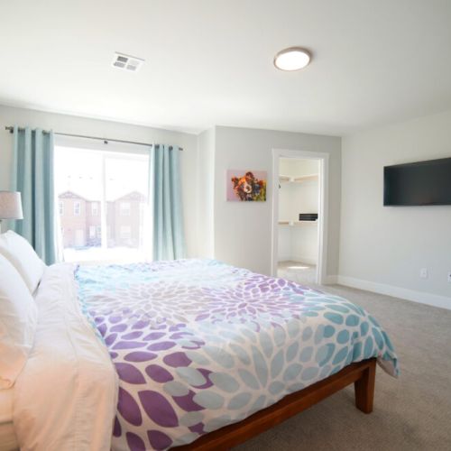 The spacious master bedroom enjoys a king bed, a large walk-in closet, a flat-screen TV, and an en suite bathroom.