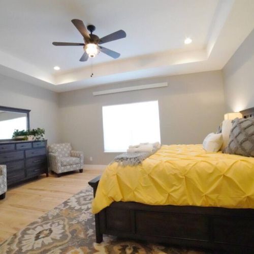 The spacious master bedroom enjoys a king bed, a chest of drawers, a couple lounge chairs, and an en suite bathroom.