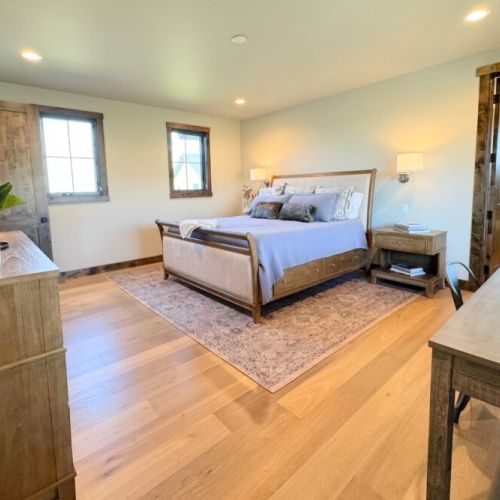 The primary bedroom features a king bed, a dedicated workspace, a smart TV with a soundbar, and an expansive en suite bathroom.