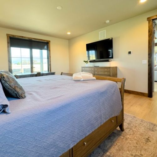 The primary bedroom features a king bed, a dedicated workspace, a smart TV with a soundbar, and an expansive en suite bathroom.