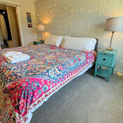 The spacious primary bedroom enjoys a king bed, a large walk-in closet, a flat-screen TV, and an en suite bathroom.